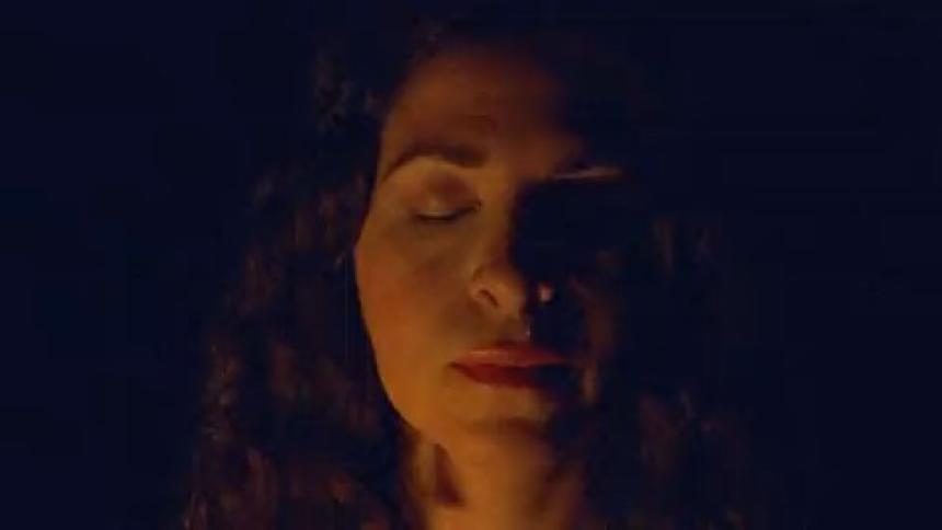 A bright white light interrupted by a flash of a woman with her eyes closed in the dark