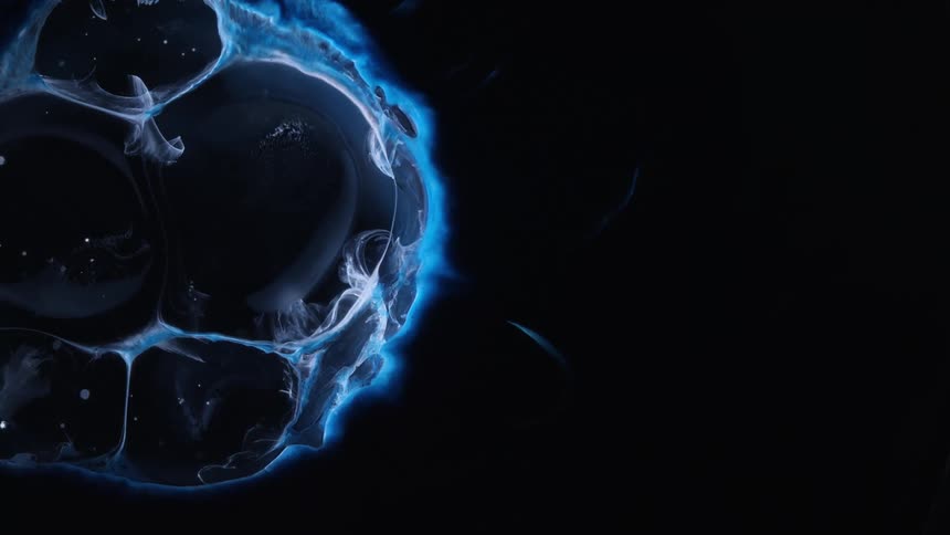 Blue colored liquid dense fluid expanding into abstract bubbles on a black background
