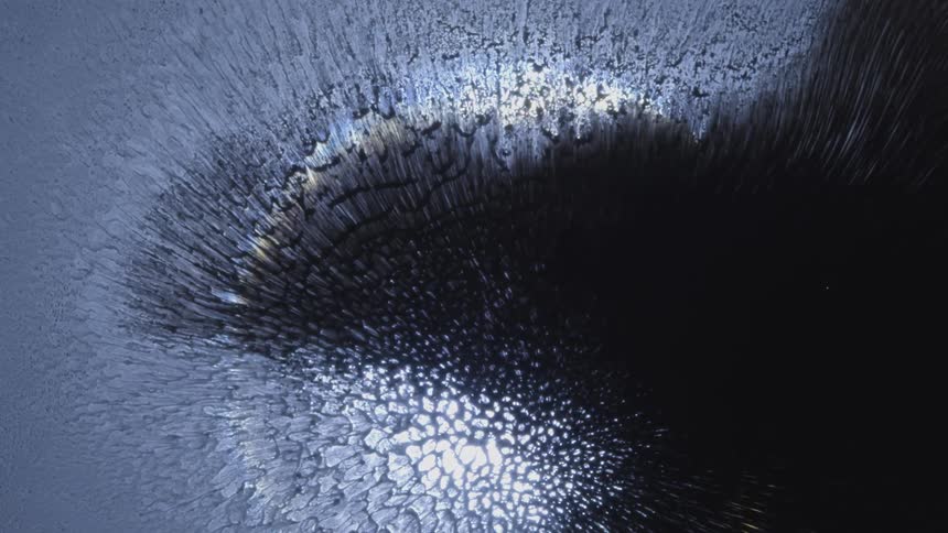 Several white particles are moving forward on a black background and then a colored circle appears