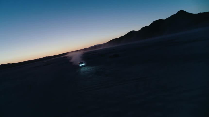 A view of a truck driving outdoors at night in the desert