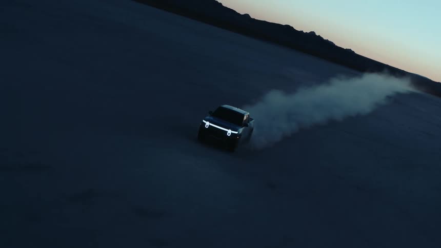 A pick up truck speeding across the desert at dusk