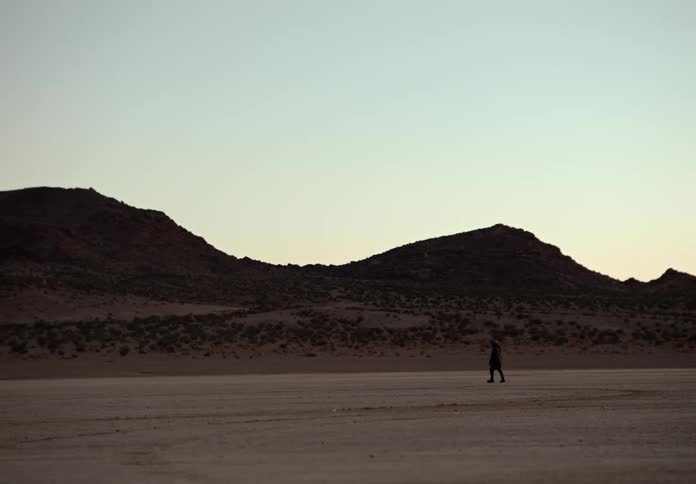 A man uses a metal detector in the desert