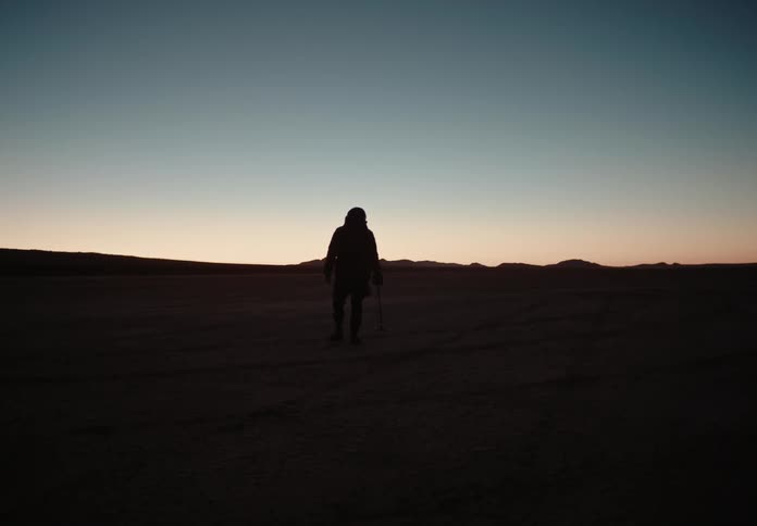 A man walking out in a desert at dusk