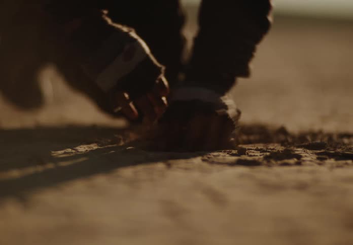 A man digs an object out of dry soil
