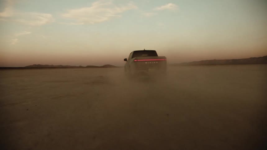 A pick up truck driving across the desert sand