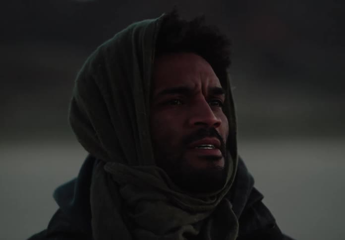 A man in the desert removes the cloth covering his mouth to breathe better for a moment then puts it back in place