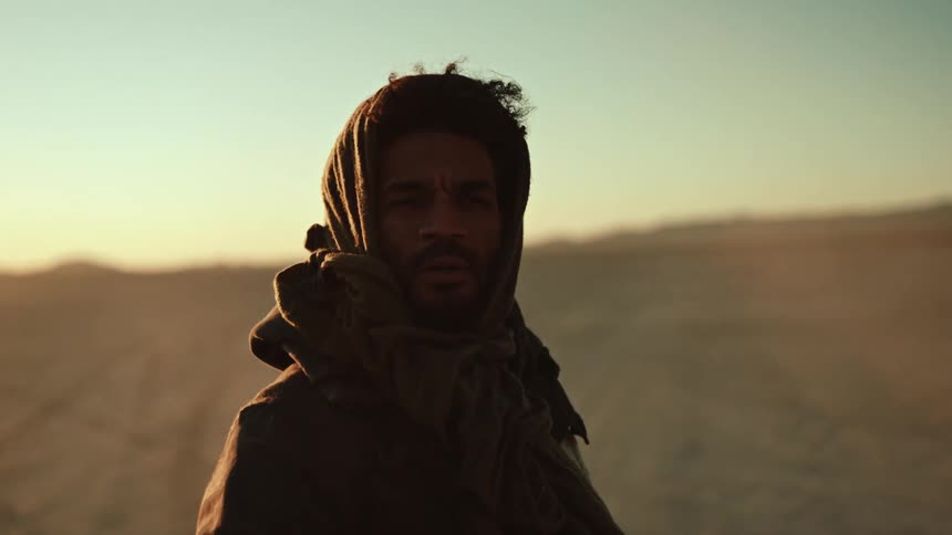 A man is standing alone in the desert