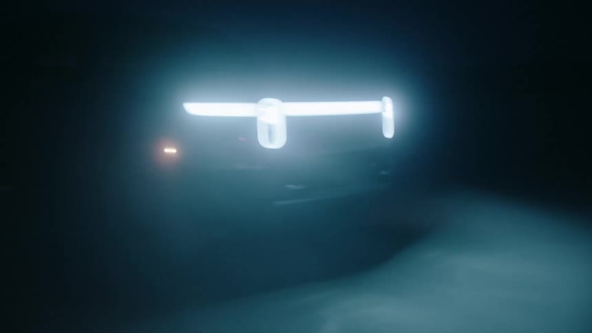 A pick up truck driving across the desert at night its headlights the only light source