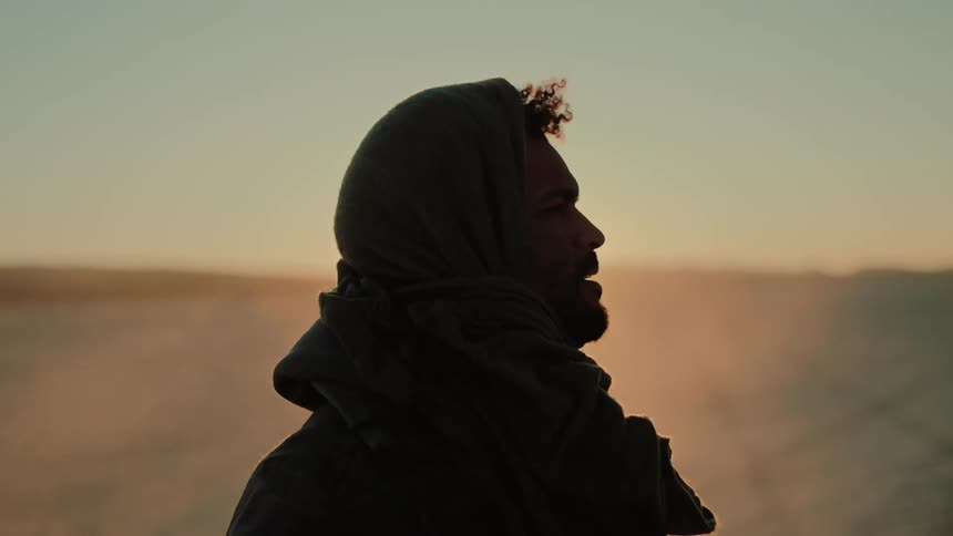 A tired man standing in the desert looks around