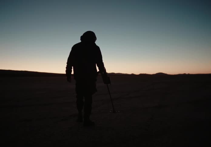 A man searches the ground with a metal detector