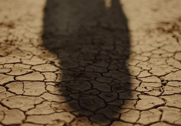 A shadow moves over cracked earth