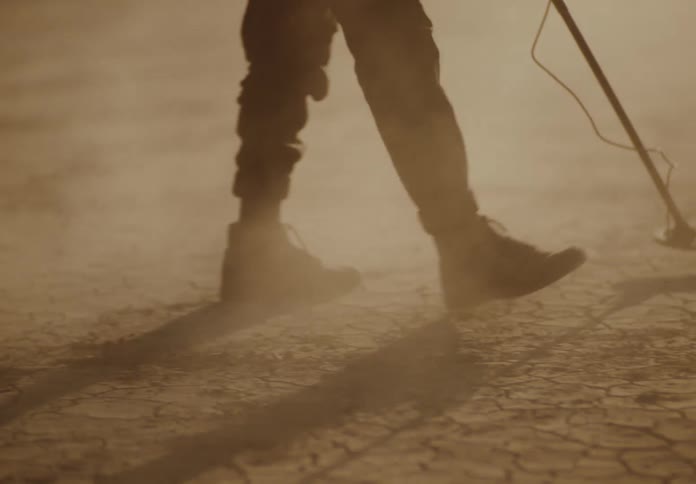 A man is searching the desert with a metal detector
