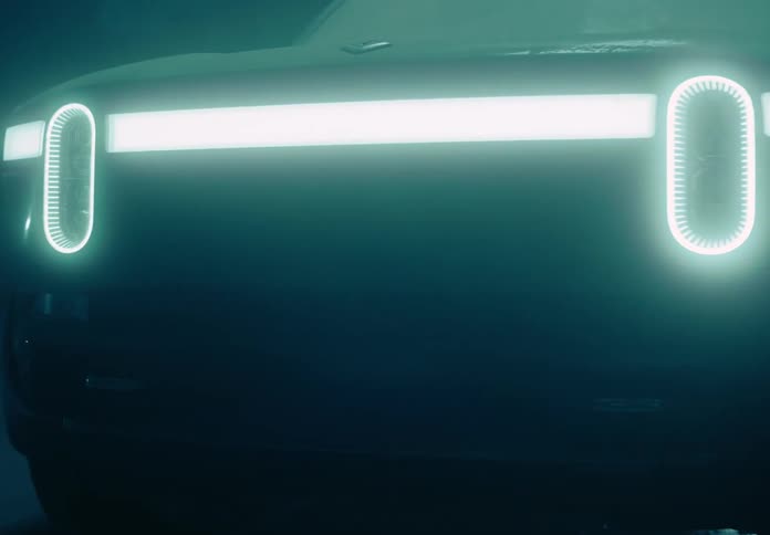 A pick up truck in a dark garage with its headlights on and covered in dirt