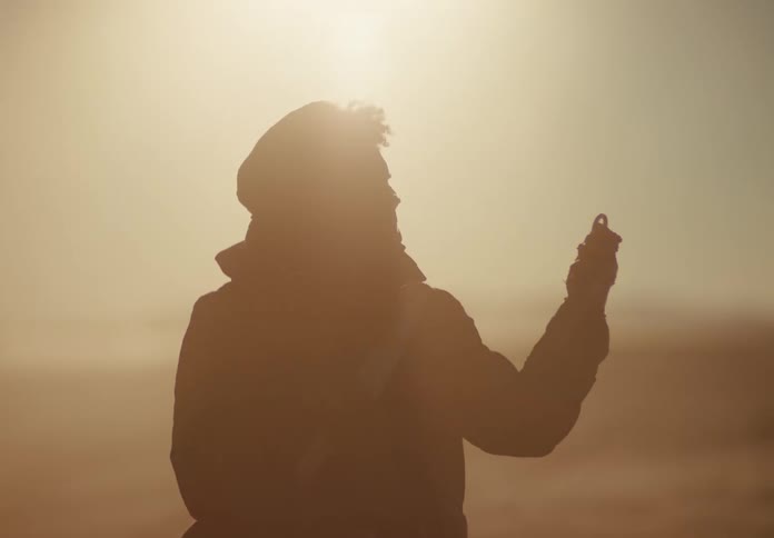 Man crouched on the ground finding a metallic object in dry desert soil