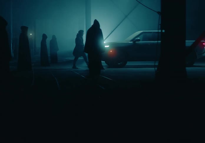 Hooded people in a lowlight environment in the dark are facing a pickup truck with one of them entering the vehicle