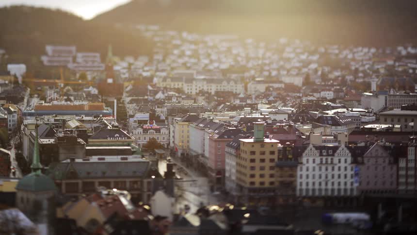 Vehicles drive along the streets of a city that has many buildings packed together