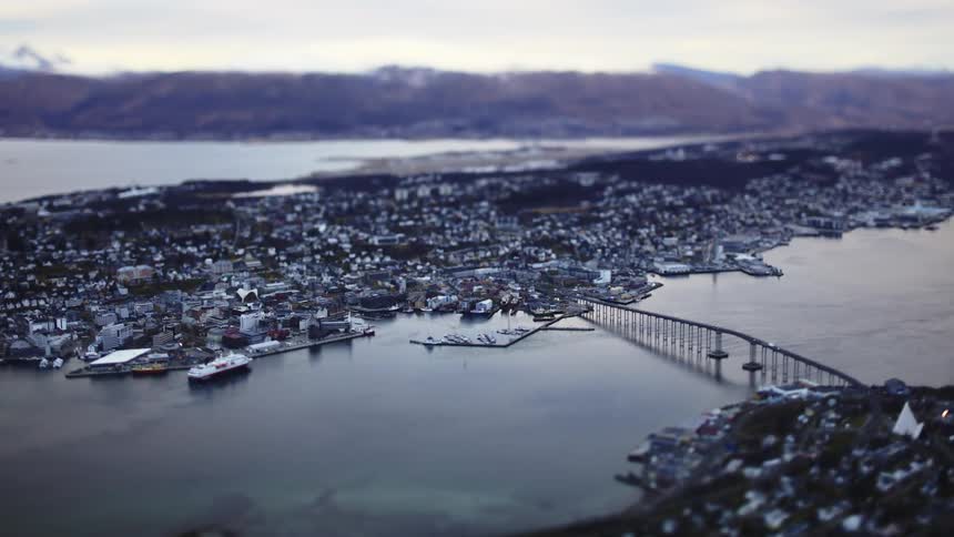 A coastal city nestled between a calm sea and mountainous terrain