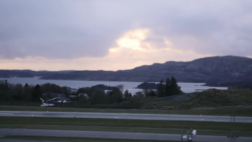 Helicopter taking off on a runway next to a lake in mountains on a morning