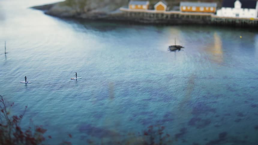 Two people paddle board away from the island