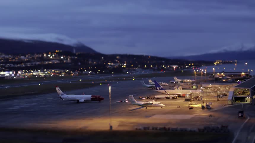 A commercial airplane being pulled from a hangar then turning to head to a runway