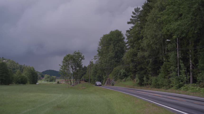 Gray car passing on a road in a natural environment with trees around and sending one side