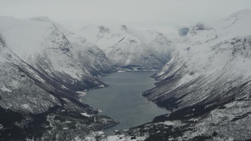 A snowy mountain range surrounds a calm dark lake