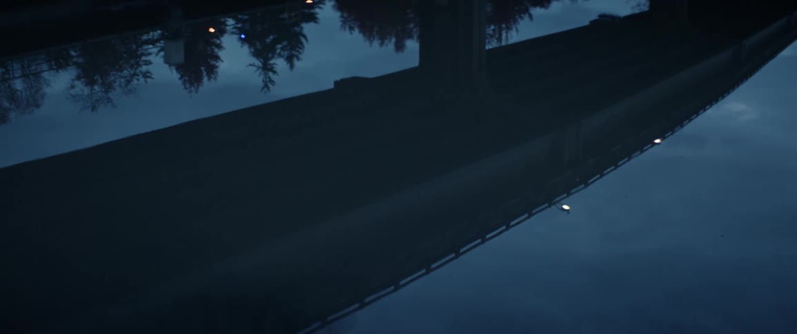 Water reflects the silhouette of a roadway at dawn
