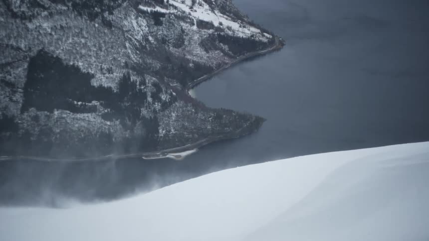 Wind lifting snow dust off the side of a snow covered mountain