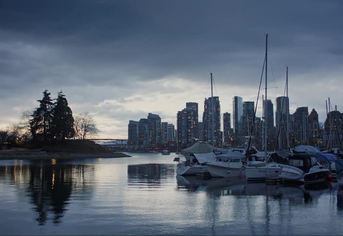 Water flows past marina and nearby city against a red tinted horizon