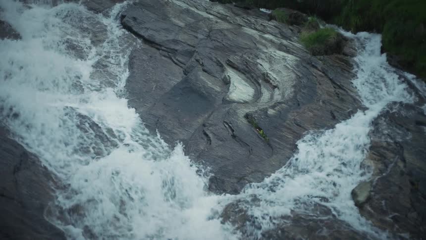 River forks briefly and forms whitewater while it flows down stone slope