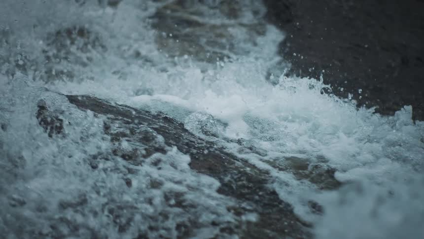 A close up of a waterfall crashes into a river