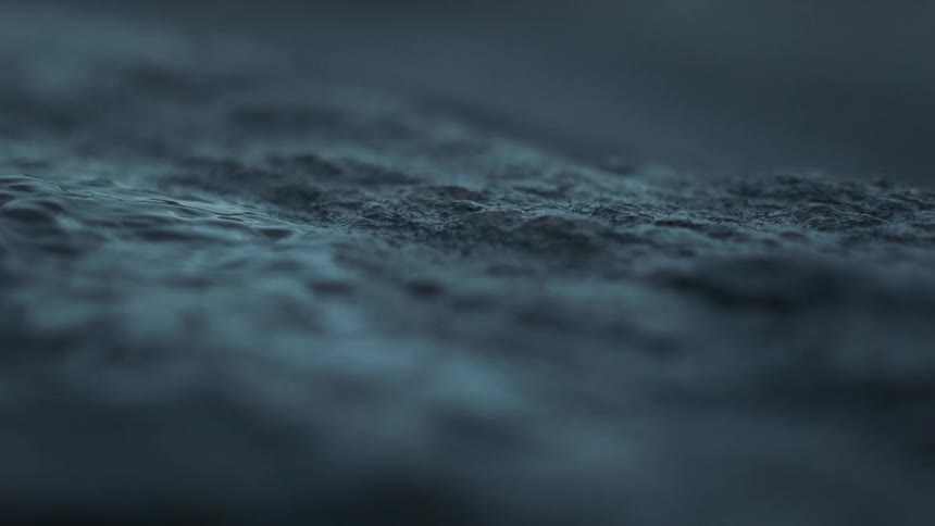 Some water running over the rough surface of a stone on the ground