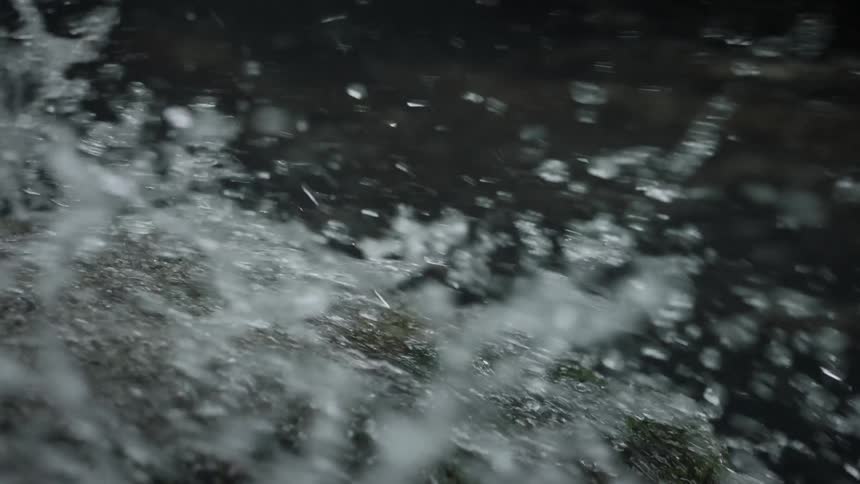 Closeup of the running water of a river over a rock in slow motion