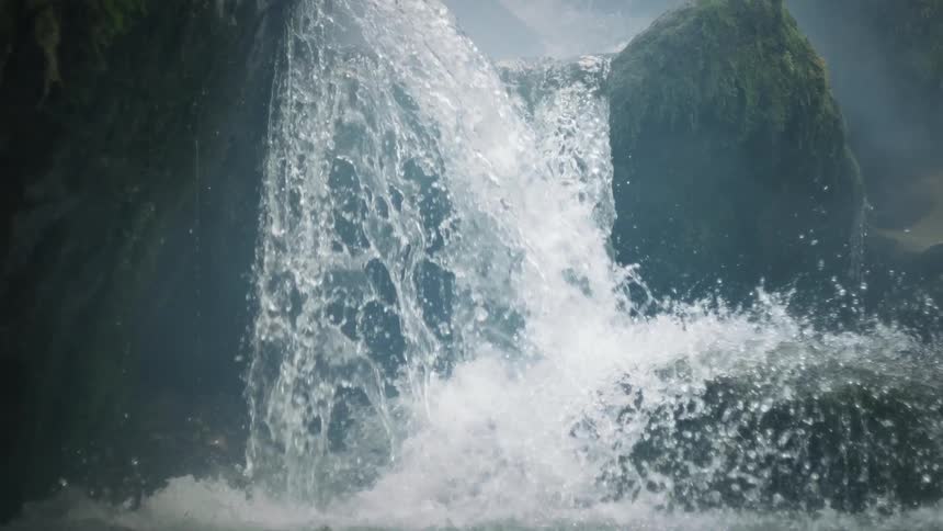 Water flows down a series of waterfalls onto boulder near the riverbank on a foggy day