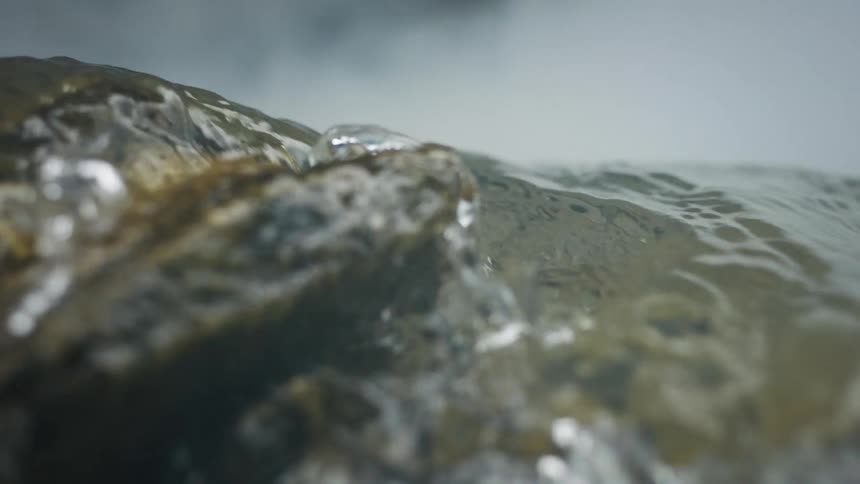 Close up of water flowing in slow motion over rocks