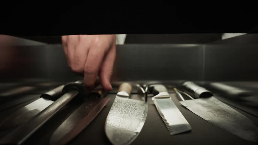 A chef takes a knife from the drawer