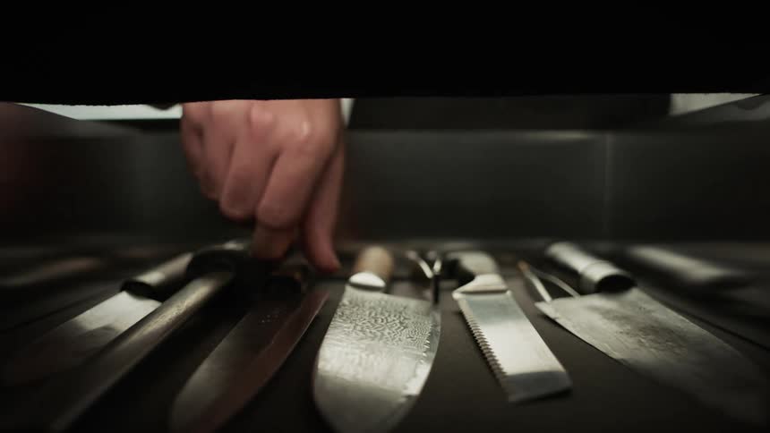 A man removes a knife from a drawer