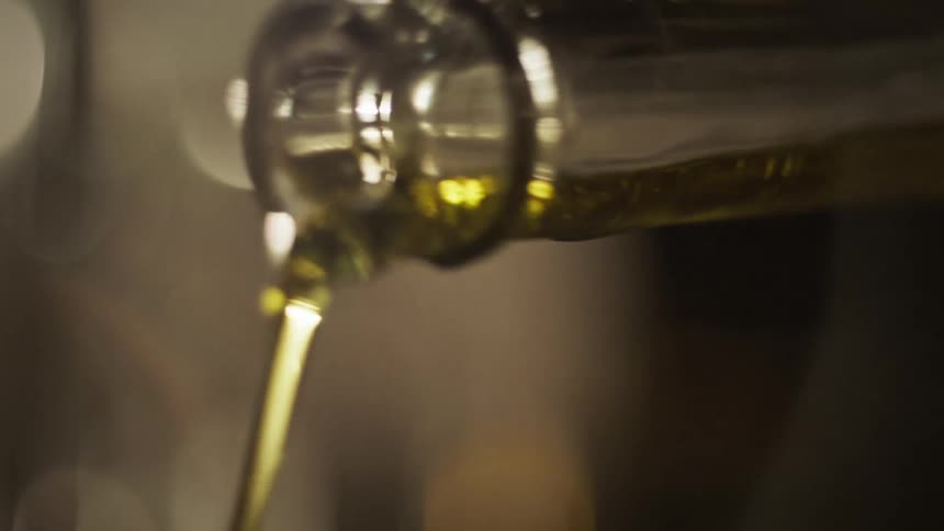 Person pours green liquid from long necked bottle