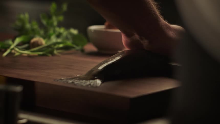 A person is filleting a fish on a wooden cutting board