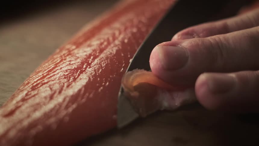 A person is filleting a fish on a wooden cutting board