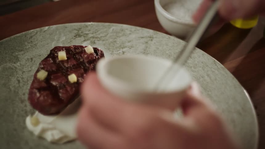 Chef places garnish onto plated meal with a pair of tweezers