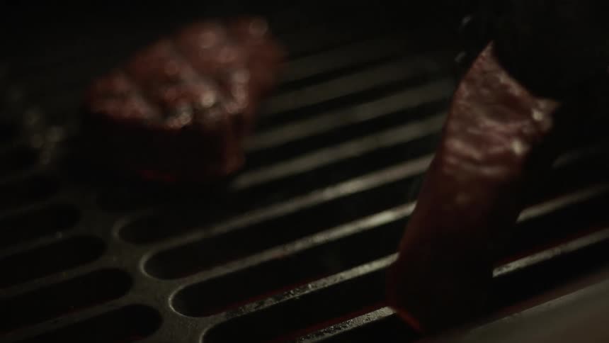 A person flips the steaks on the grill
