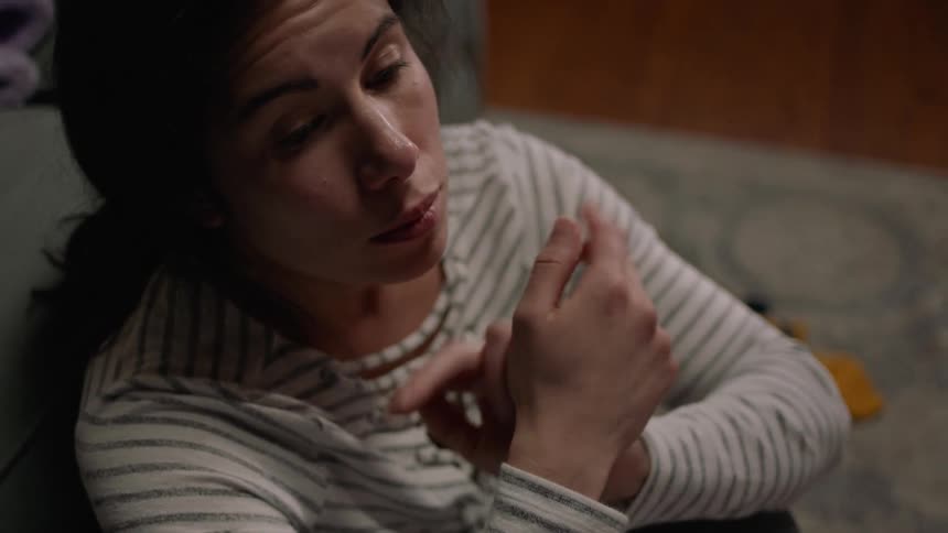 A woman rubs her temples sitting on the floor