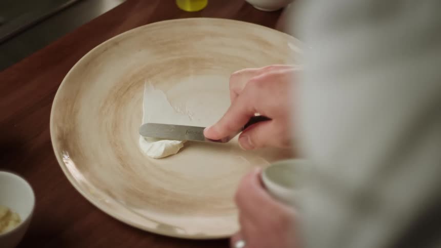 A person spreads sauce on the plate
