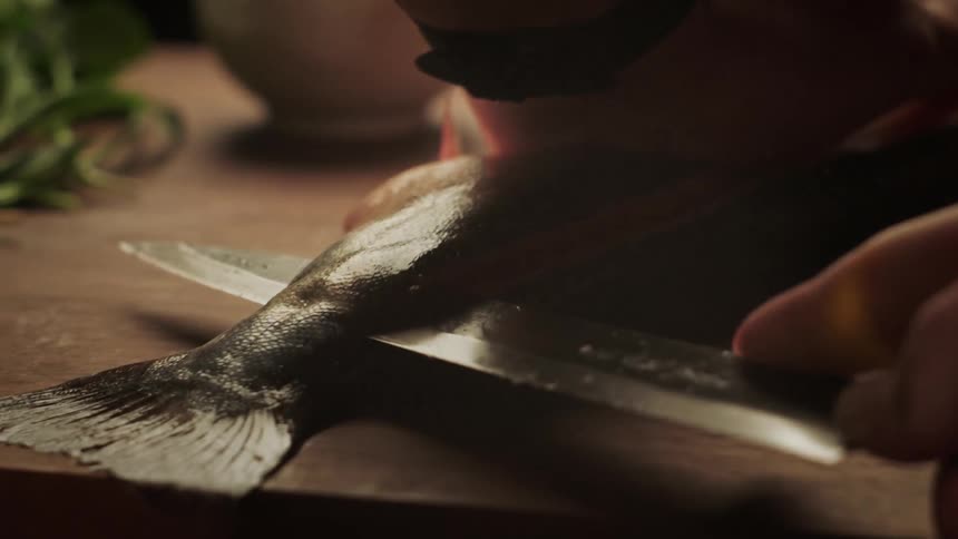 A person is cutting a fish on a cutting board