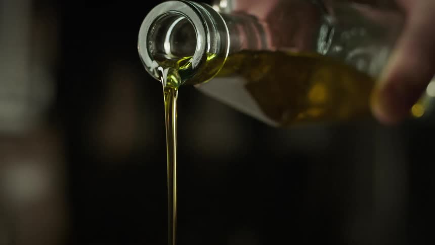 A person pours oil from a bottle