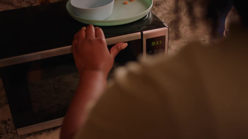 A woman warms her coffee in the microwave