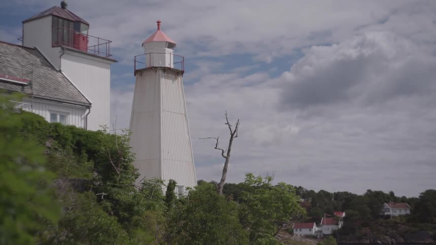 A lighthouse sits in the trees as the breeze blows through on sunny day