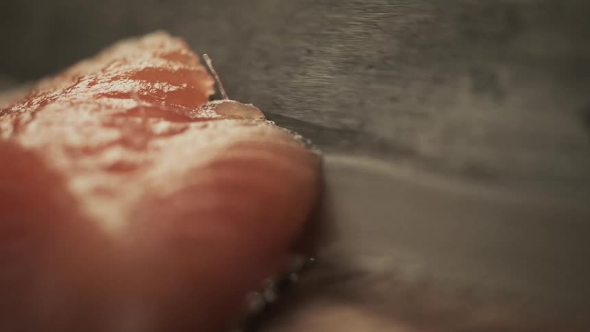 The knife cuts a piece of fish