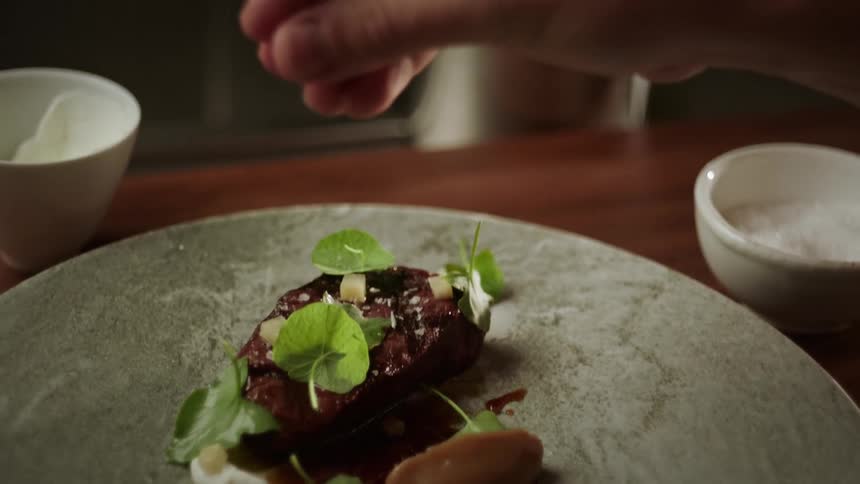 A man seasoning a meal in slow motion